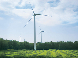 Close-up of several wind turbines set against a natural backdrop