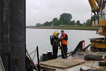 Divers and workers on a ship with a dredger
