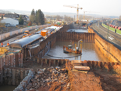 Dredging the bottom of an excavation pit using a suction dredger