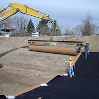 Workers deploying Huesker Canal³ membrane with excavator