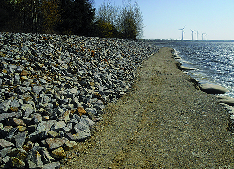 A riverbank with large stones and a gravel path