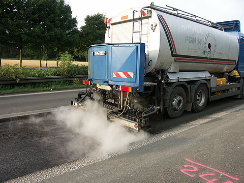 A lorry is carrying out resurfacing work on a motorway.