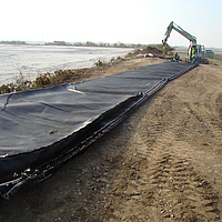 Employees work on the Basetrac® Woven reinforcement fabric in preparation for installation