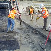 Construction workers applying concrete over Huesker Canal³ membrane
