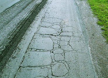 An old country road with numerous cracks in the surface