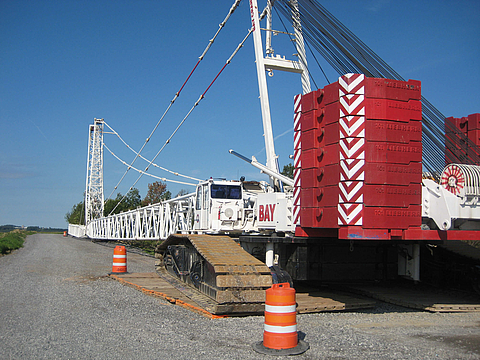 A large crane is standing on the ground reinforcement for a wind turbine