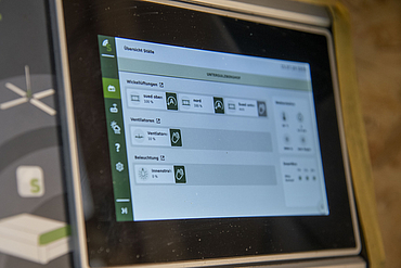 A close-up view of a Lubratec SmartPad installed in a dairy cow barn, showing various settings on its built-in display