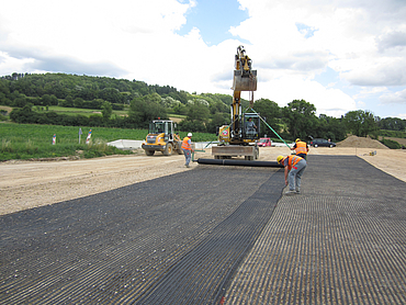 Fortrac is being laid using an excavator and a team of workers